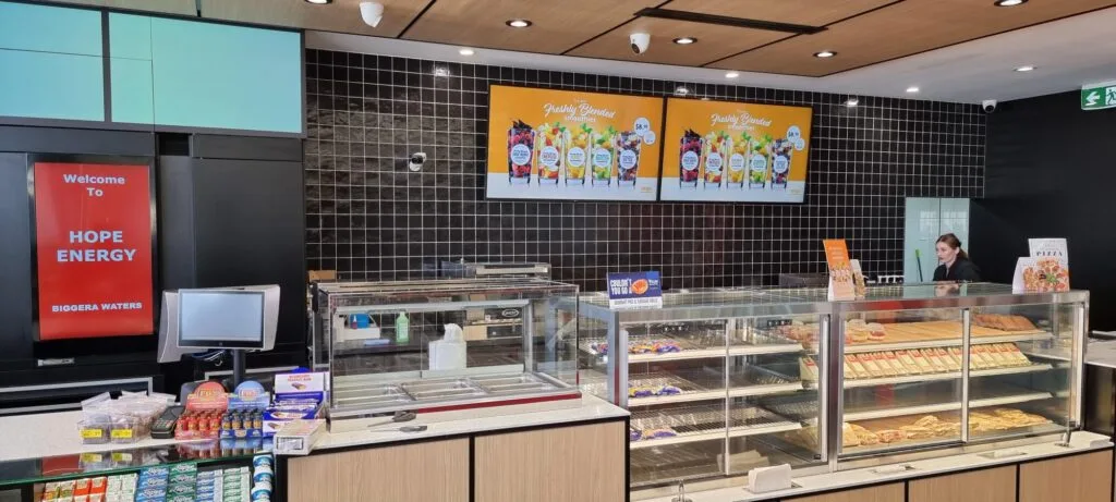 Digital menu screens advertising smoothies above the food counter at Hope Energy Biggera Waters